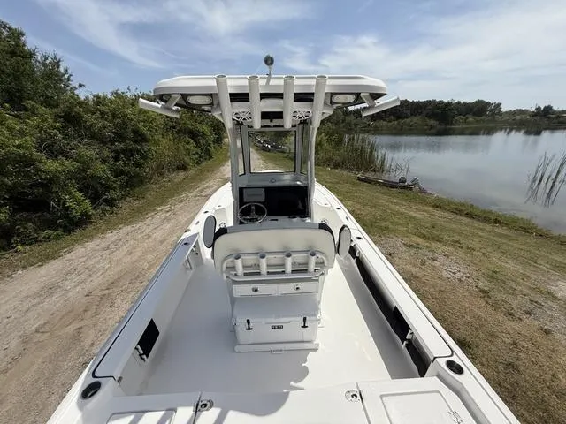 Slide: The Image of 2024 Tidewater 2410 Bay Max boat on a lakeside dirt path, showcasing interior and console. - 13