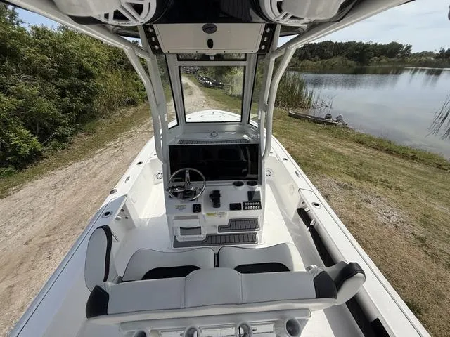 Slide: The Image of 2024 Tidewater 2410 Bay Max boat interior with console and seating, near a serene lakeside. - 14