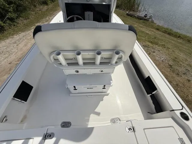 Slide: The Image of 2024 Tidewater 2410 Bay Max boat interior with rod holders and seating, near a lake. - 28