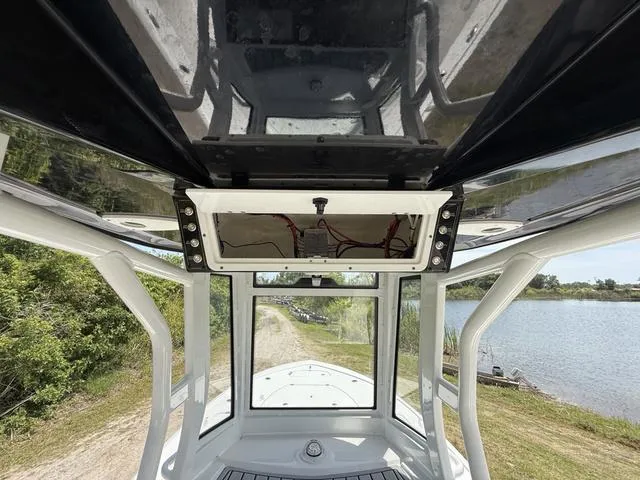 Slide: The Image of 2024 Tidewater 2410 Bay Max boat interior view with overhead electronics, near a serene lakeside. - 33