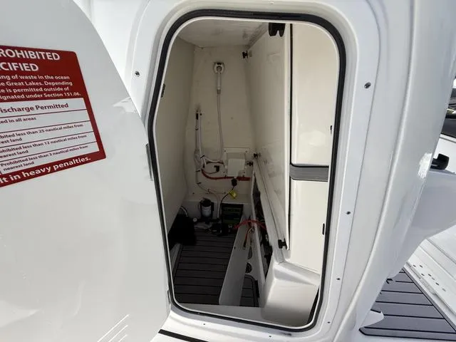 Slide: The Image of 2024 Tidewater 2410 Bay Max boat interior storage compartment with equipment and safety notice. - 35