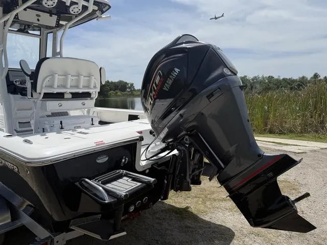 Slide: The Image of 2024 Tidewater 2410 Bay Max boat with Yamaha engine, parked near water, airplane overhead. - 6