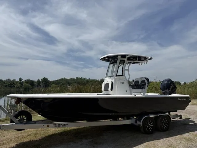 Slide: The Image of 2024 Tidewater 2410 Bay Max boat on trailer by a lake under a cloudy sky. - 9