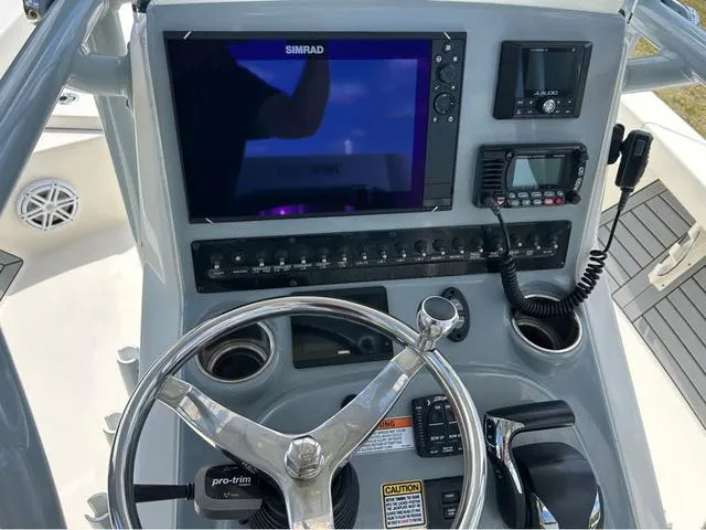 Slide: The Image of 2021 Pathfinder 2600 HPS boat dashboard with steering wheel, Simrad display, and control panel. - 12