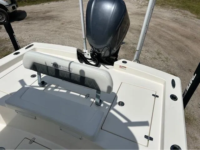 Slide: The Image of 2021 Pathfinder 2600 HPS boat interior with seating and motor, parked on gravel. - 17