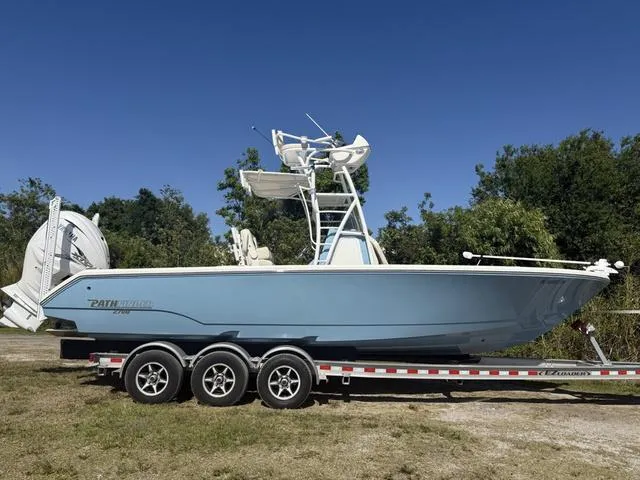 Slide: The Image of 2023 Pathfinder 2700 Open boat on trailer, side view, outdoors with trees in background. - 2