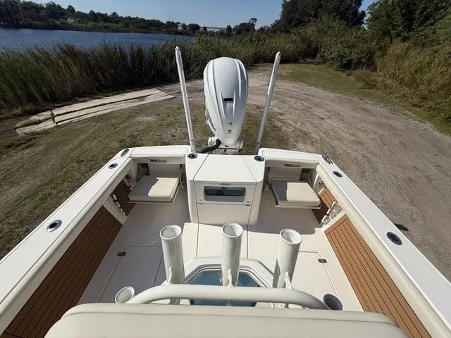 Slide: The Image of 2023 Pathfinder 2700 Open boat interior with seating and rod holders by a lake. - 27