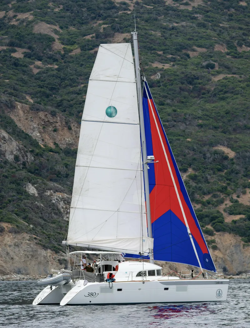 Slide: The Image of 2016 Lagoon 380 catamaran sailing near a rocky coastline. - 2
