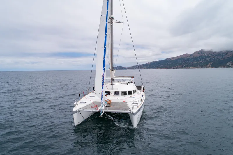 Slide: The Image of 2016 Lagoon 380 catamaran sailing on open sea with mountainous coastline in background. - 3