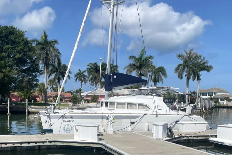 Slide: The Image of 2016 Lagoon 380 catamaran docked in a sunny marina with palm trees. - 4