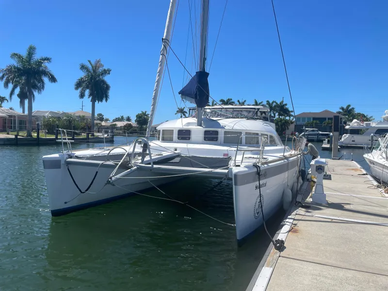 Slide: The Image of 2016 Lagoon 380 catamaran docked in a sunny marina with palm trees. - 6