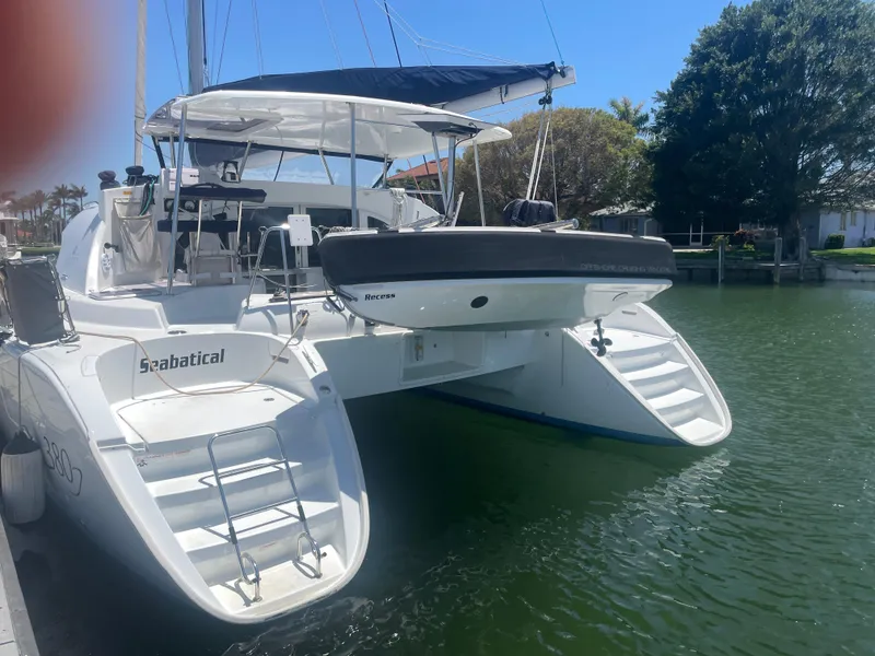 Slide: The Image of 2016 Lagoon 380 catamaran docked, featuring dual staircases and a small boat on deck. - 7