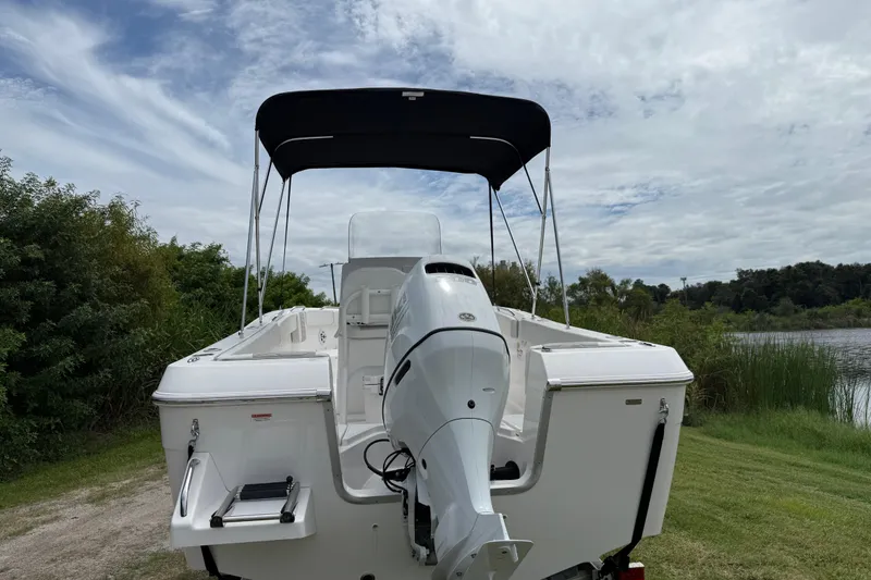 Slide: The Image of 2024 Aquasport 2100 CC boat with outboard motor, parked near a scenic lake. - 3