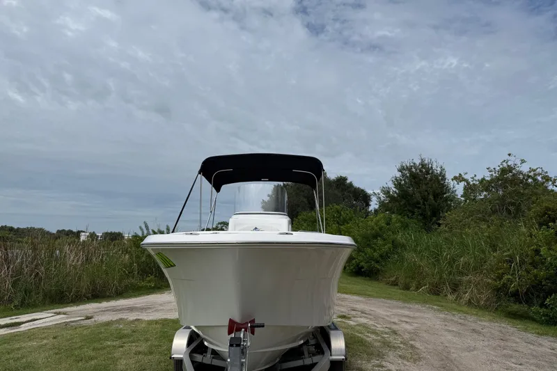 Slide: The Image of 2024 Aquasport 2100 CC boat on trailer, surrounded by greenery under cloudy sky. - 4
