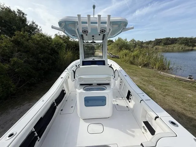 Slide: The Image of 2024 Tidewater 256 CC Adventure boat, white interior, docked near lush greenery and calm water. - 14
