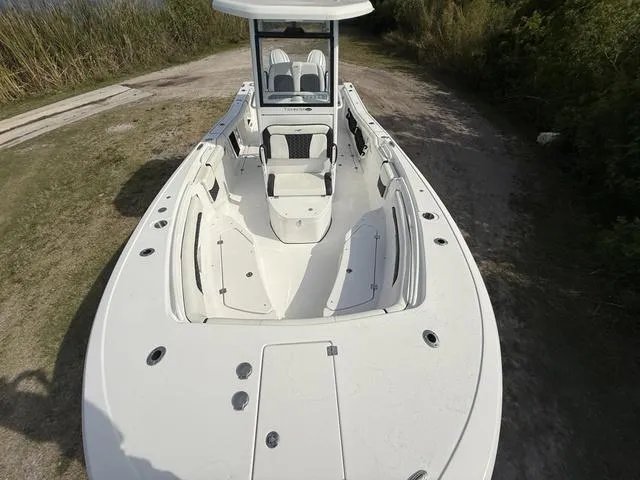 Slide: The Image of 2024 Tidewater 256 CC Adventure boat on a dirt path, showcasing spacious deck and seating. - 27