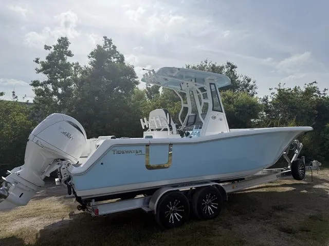 Slide: The Image of 2024 Tidewater 256 CC Adventure boat on trailer, light blue hull, parked outdoors. - 3