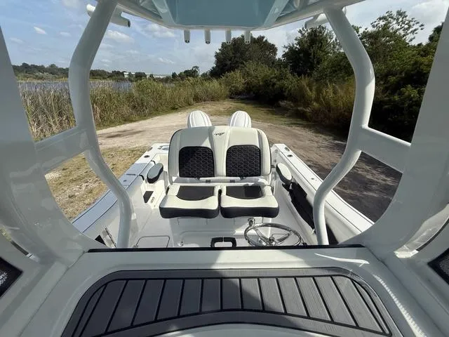 Slide: The Image of 2024 Tidewater 256 CC Adventure boat interior with seating, viewed from helm, near water and greenery. - 32
