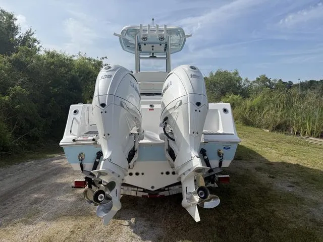Slide: The Image of 2024 Tidewater 256 CC Adventure boat with dual outboard engines, parked on grassy area. - 4