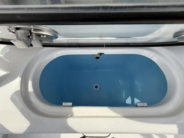 Slide: The Image of 2024 Tidewater 256 CC Adventure boat livewell, featuring a blue interior and secure lid. - 40