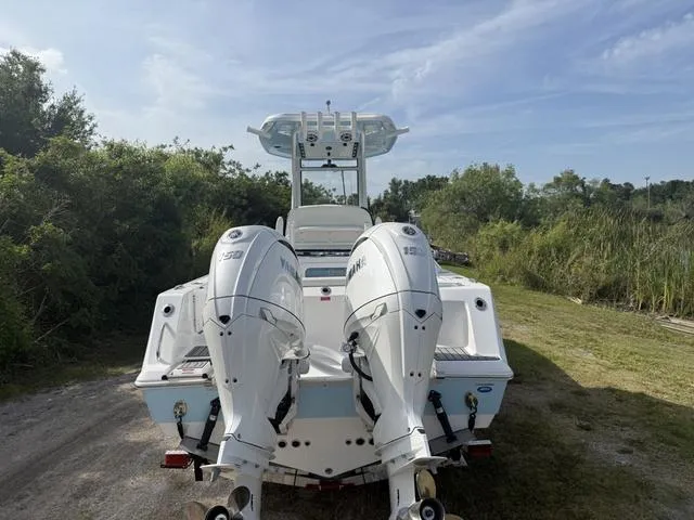 Slide: The Image of 2024 Tidewater 256 CC Adventure boat with dual outboard engines, parked on grassy area. - 5