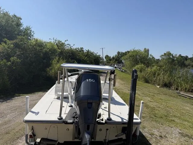 Slide: The Image of 2009 Hewes 18 Redfisher boat with 150 HP engine, parked near lush greenery. - 5