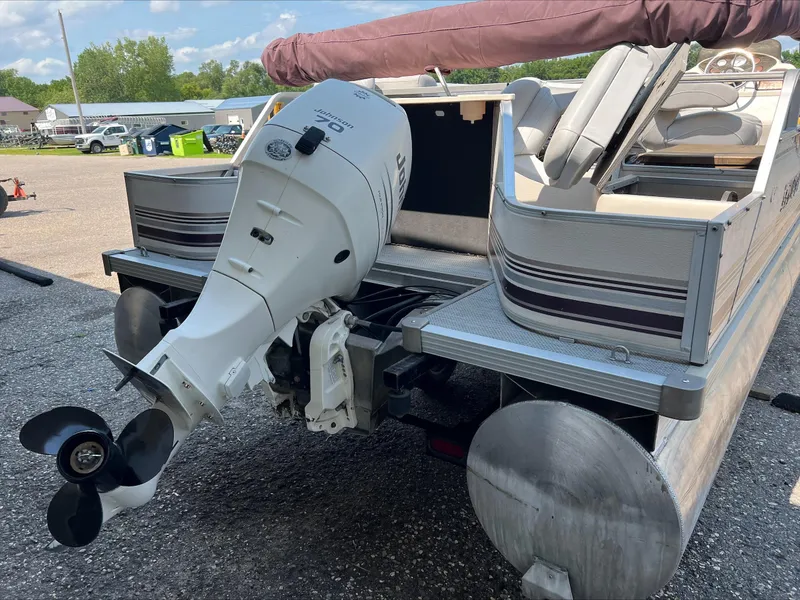 Slide: The Image of 2003 Manitou Osprey pontoon boat with Johnson outboard motor in a parking lot. - 3