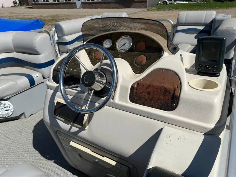 Slide: The Image of 2003 Manitou Osprey boat dashboard with steering wheel, gauges, and seating. - 6