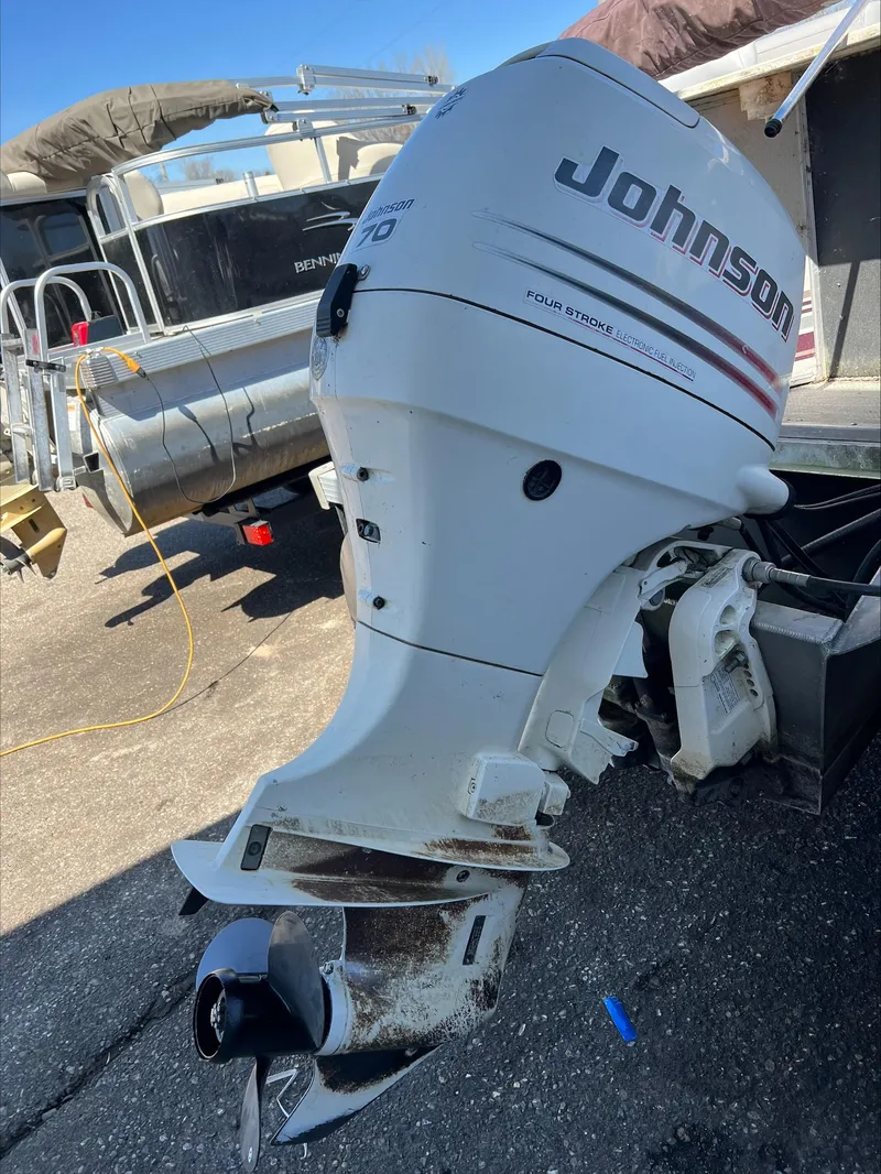 Slide: The Image of 2003 Manitou Osprey with Johnson outboard motor, parked on a sunny day. - 8