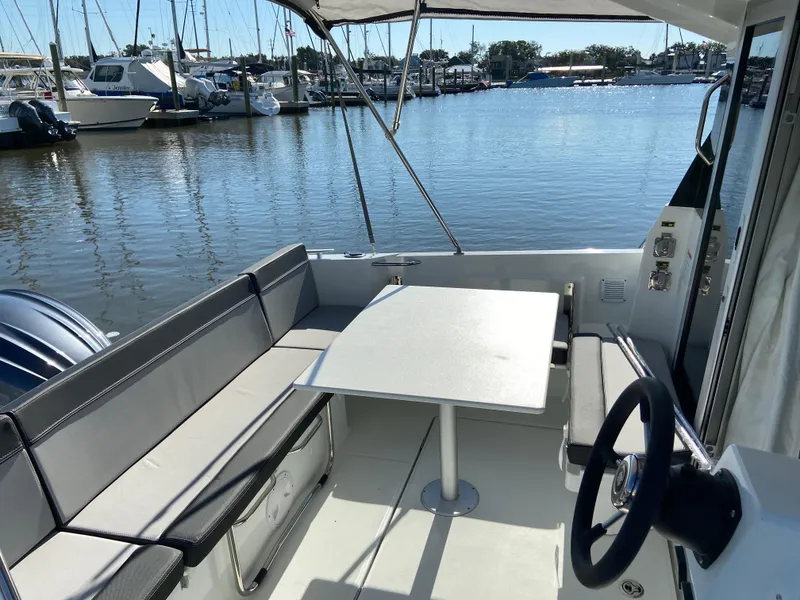 Slide: The Image of 2021 Jeanneau NC795 S2 boat interior with seating and table, docked at marina. - 8