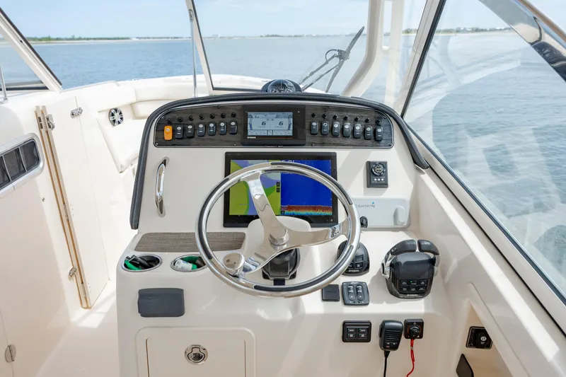 Slide: The Image of 2020 Grady-White Freedom 307 boat dashboard with steering wheel and navigation controls. - 17