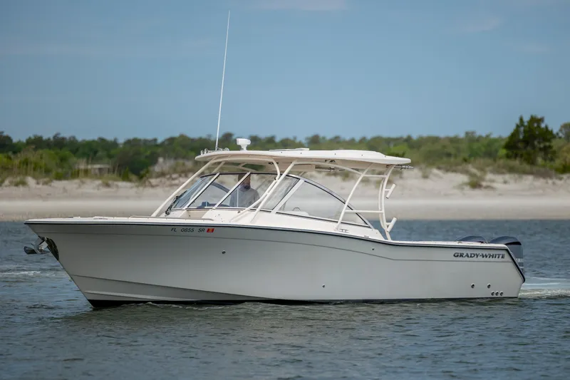 Slide: The Image of 2020 Grady-White Freedom 307 boat cruising on calm waters near a sandy shoreline. - 5