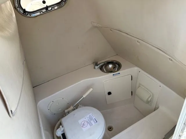 Slide: The Image of 2005 Pursuit 2570 Center Console boat interior with compact marine toilet and sink. - 10