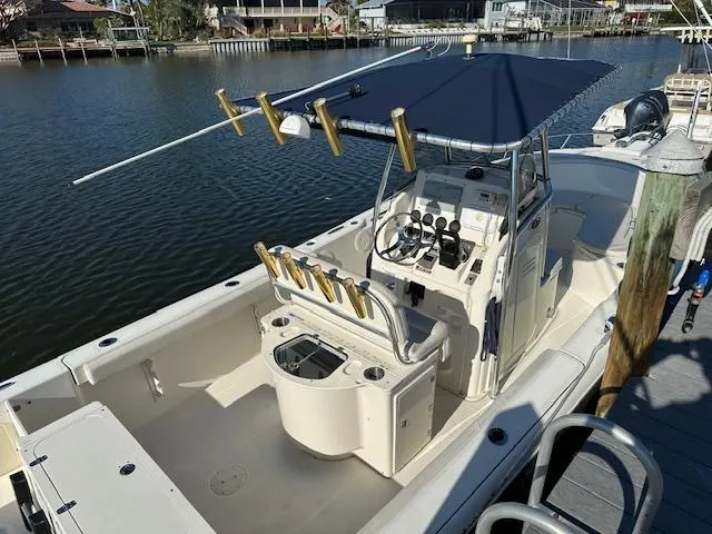 Slide: The Image of 2005 Pursuit 2570 Center Console boat docked by a calm waterfront. - 2