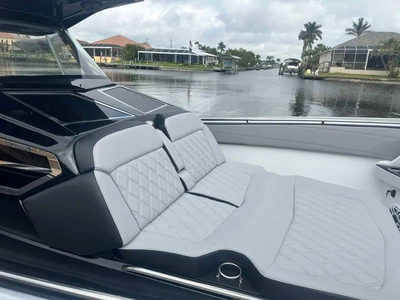 Slide: The Image of 2025 Nor-Tech 400 Supersport luxury boat interior with gray seating, docked by a scenic canal. - 7