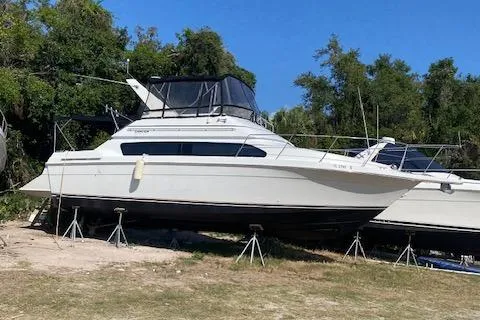 The Image of 1998 Carver 380 Santego yacht on stands, surrounded by trees, under clear blue sky. - 0