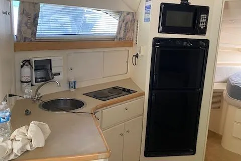 Slide: The Image of 1998 Carver 380 Santego yacht kitchen with sink, stove, microwave, and refrigerator. - 12