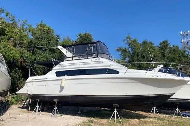 Slide: The Image of 1998 Carver 380 Santego yacht on stands, surrounded by trees, under clear blue sky. - 3