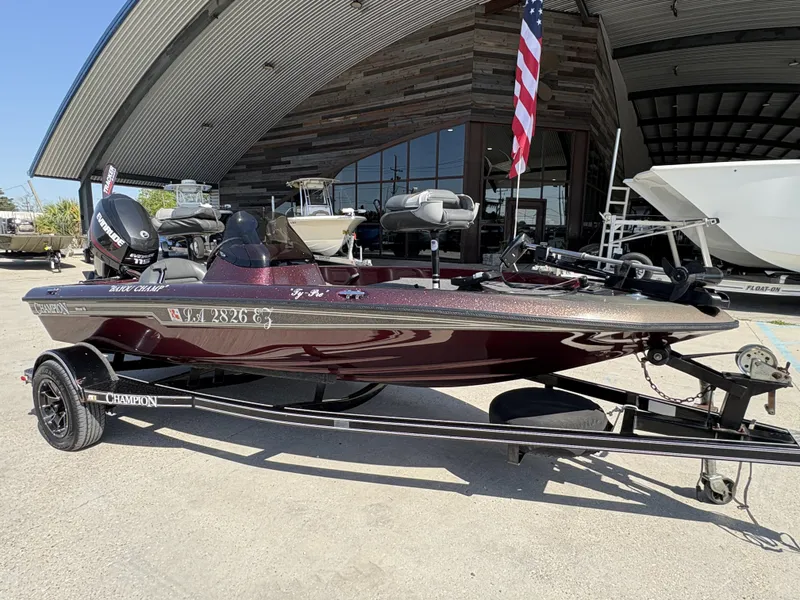 Slide: The Image of 1999 Champion MEAN 16 boat with trailer, parked outside a modern building. - 2