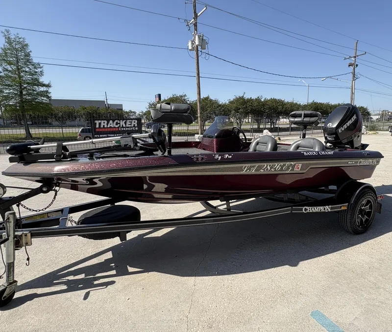 Slide: The Image of 1999 Champion MEAN 16 boat with Evinrude motor on trailer, parked outdoors. - 3