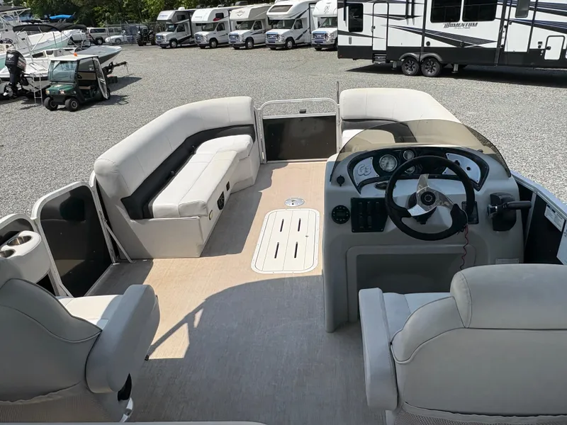 Slide: The Image of 2020 G3 SunCatcher pontoon boat interior with seating and steering wheel, parked in RV lot. - 12