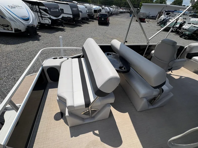 Slide: The Image of 2020 G3 SunCatcher boat interior with beige seating and table, parked among RVs. - 22