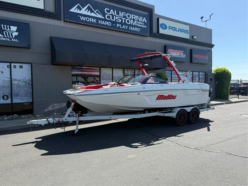 Slide: The Image of 2023 Malibu Wakesetter 23 MXZ boat on trailer outside dealership. - 1