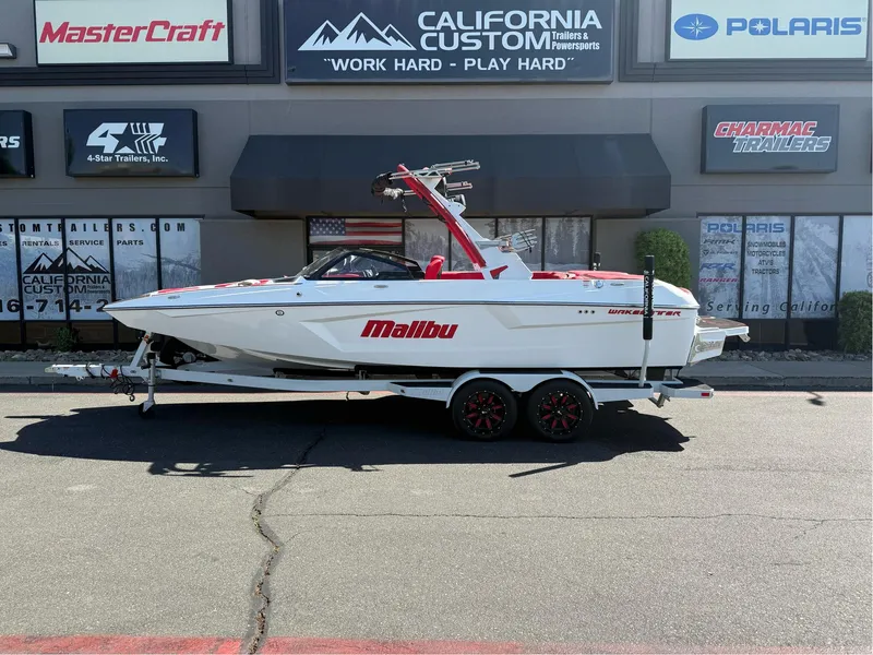 Slide: The Image of 2023 Malibu Wakesetter 23 MXZ boat on trailer, parked outside dealership. - 2