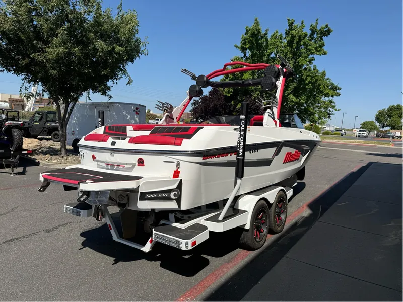 Slide: The Image of 2023 Malibu Wakesetter 23 MXZ boat on trailer, parked outdoors, sunny day. - 4