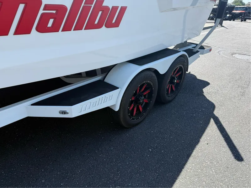 Slide: The Image of 2023 Malibu Wakesetter 23 MXZ boat trailer with red-accented wheels. - 8