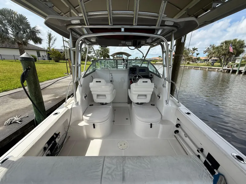 Slide: The Image of 2013 Robalo R245 Walkaround boat interior with dual seats, docked by a canal. - 11