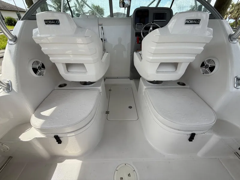 Slide: The Image of 2013 Robalo R245 Walkaround boat interior with dual white seats and storage compartments. - 13