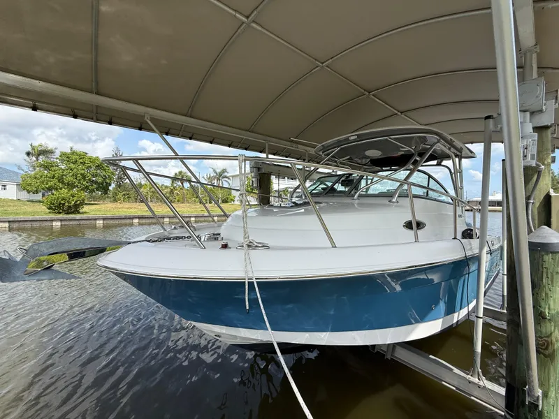Slide: The Image of 2013 Robalo R245 Walkaround boat docked under a canopy. - 2