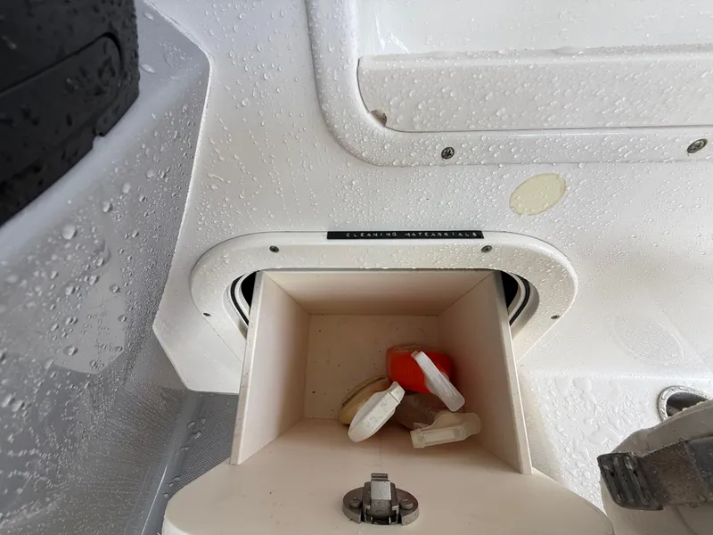 Slide: The Image of Storage compartment on a 2013 Robalo R245 Walkaround boat, featuring wet surfaces and safety gear. - 23